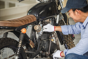 Young man fixing motorcycle in workshop garage, Man repairing motorcycle in repair shop, Mechanical hobby and repairs concepts