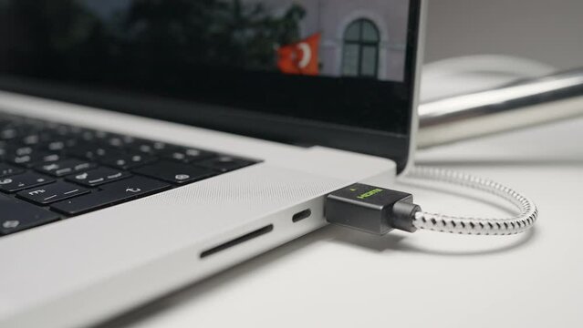 Closeup of USB flash drive inserted into port on the side of a laptop. Action. Part of laptop with a screen and movie.