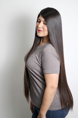 Latin young adult woman shows how silky and shiny her black hair is, very long, straight, very happy and proud of the beautiful hair with a beautiful haircut	