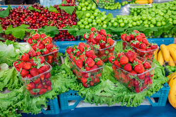 Strawberry, cherry and other sweet fruits for sale on a shelf of a farmers market. Fresh and healthy food, rich with vitamins