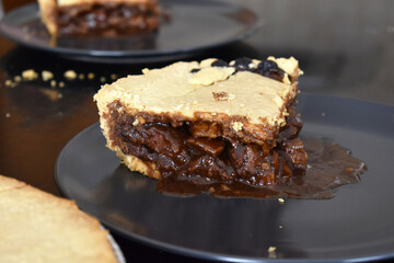 Steak pie on a black plate.