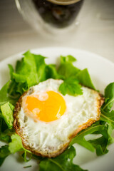 one fried egg with arugula and lettuce in a plate