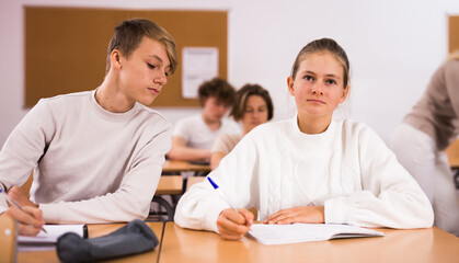 Obraz premium Diligent teenage high school students studying in college with classmates, making notes of teacher lecture