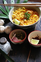 Khao Soi Recipe,Khao Soi,Khao Soi Kai, Thai Noodles Khao Soi, Chicken Curry with seasoning served on black wooden table with decorative leaves, vertical photo.