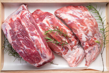 Pork Spare Ribs on black wooden table, Raw Pork ribs with with a rosemary on wooden plate.