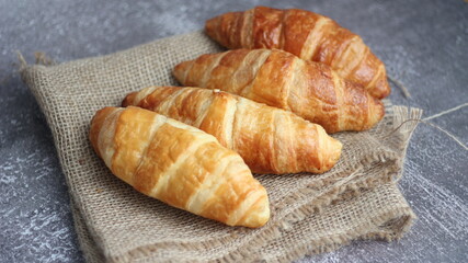 Croissant bread stacked on the table with wooden plates and sackcloth.