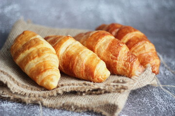Croissant bread stacked on the table with wooden plates and sackcloth.