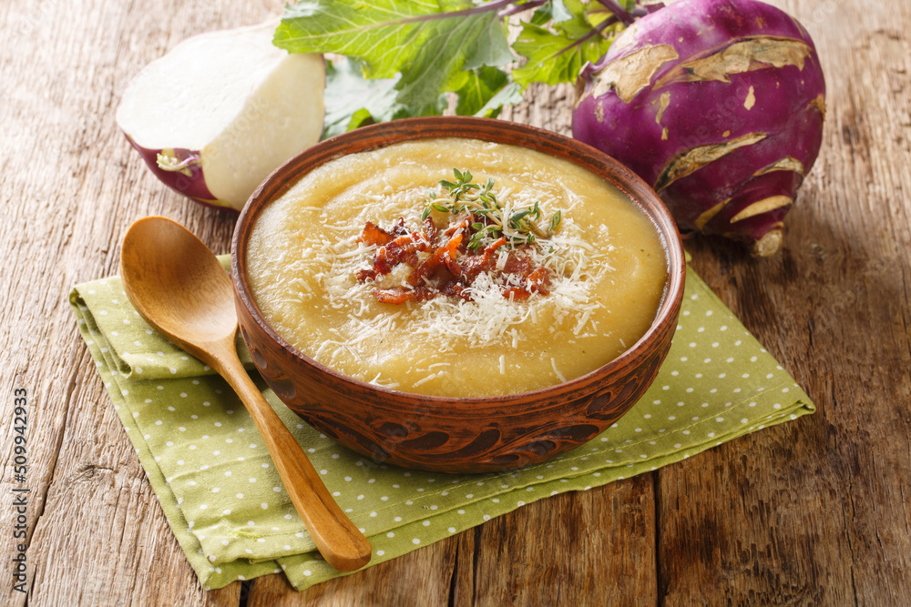 Wall mural creamy pureed kohlrabi soup with bacon and parmesan close-up in a bowl on the table. horizontal