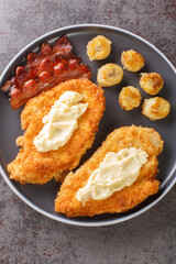 Chicken a la Maryland is fried chicken that is dressed with a gravy and accompanied by bananas and bacon close-up in a plate on the table. Vertical top view from above