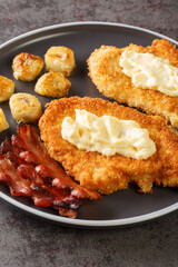 Chicken a la Maryland is fried chicken that is dressed with a gravy and accompanied by bananas and bacon close-up in a plate on the table. Vertical