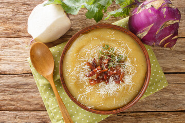Homemade healthy pureed kohlrabi soup with bacon and parmesan cheese close-up in a bowl on the...