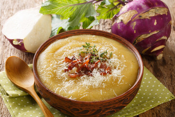 Homemade healthy pureed kohlrabi soup with bacon and parmesan cheese close-up in a bowl on the...