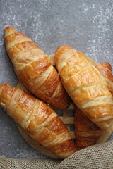 Croissant bread stacked on the table with wooden plates and sackcloth.