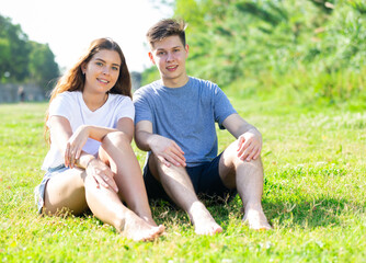 Young man and girl are resting on the grass