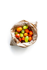 Closeup of fresh juicy organic cherry tomatoes from the garden in a craft bag on isolated white background from above
