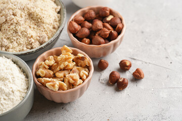 Ingredients for baking a carrot cake: finely grated carrots, grounded hazelnuts and almonds, chopped walnuts, white flour, eggs, sugar on grey background