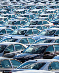 Rows of a new cars parked in a distribution center on a car factory.