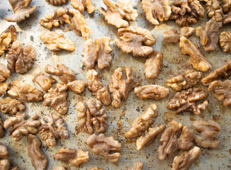 Roasted walnut lies on a metal baking sheet. Protein, healthy nuts, shortage of walnuts, more expensive snacks.
