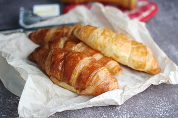 A pile of delicious fresh croissants served with butter on a gray table.