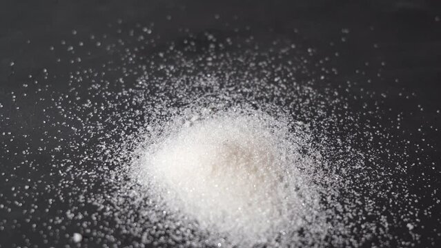 granulated sugar. pouring sugar on a black background.