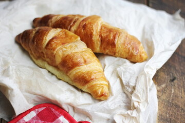 A pile of delicious fresh croissants served with butter. on the natural wood table