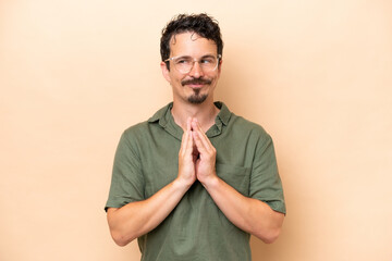 Young caucasian man isolated on beige background scheming something