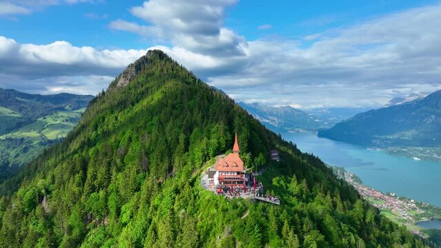 Amazing alpine landscape in Switzerland near Interlaken, flying around Harder Kulm peak on a sunny day, pine woods and Brienz lake aerial view, famous Swiss tourist attraction