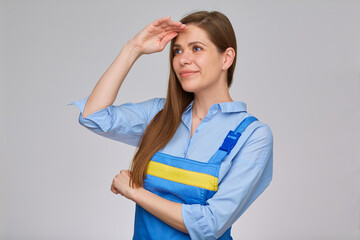 Smiling woman keeps hand near forehead and looking for a job of builder, plumber or elictrician. isolated portrait of happy worker girl with long hair.