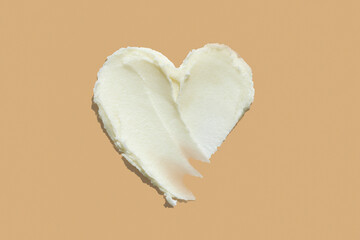 Heart shape shea butter cream texture smudge stroke on beige brown color background - obrazy, fototapety, plakaty