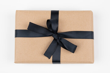 Craft gift box on a white background decorated with black ribbon. For birthday, anniversary presents, gift post cards.