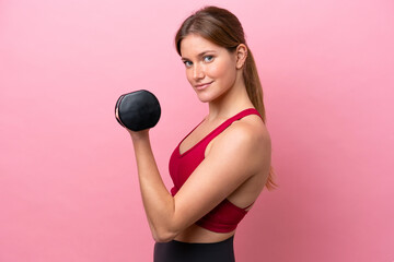 Young caucasian woman isolated on pink background making weightlifting