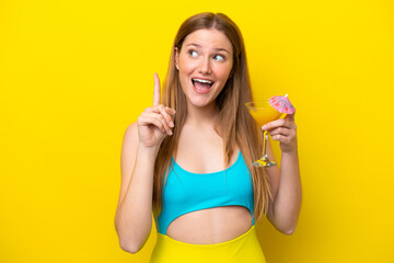 Fototapeta Young caucasian woman holding a cocktail isolated on yellow background intending to realizes the solution while lifting a finger up obraz