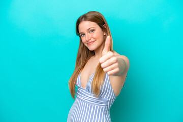 Young woman isolated on blue background in swimsuit in summer holidays and with thumb up