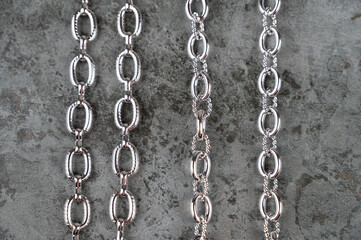 Fototapeta na wymiar Set of different chains on a concrete background. Chain connection, types of metal chains