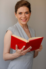 Obraz premium Happy woman teacher holding red open book. Teacher profession portrait.