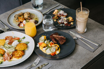 Full table at a restaurant with various dishes and drinks, served for a company of people.
