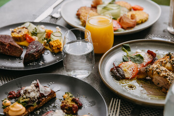 Glasses with water and juice on a table full of different dishes.