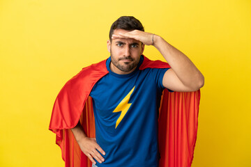 Young handsome caucasian man isolated on yellow background in superhero costume and showing...