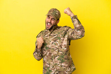 Military man isolated on yellow background celebrating a victory