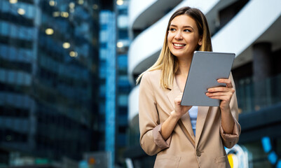 Portrait of a successful business woman using digital tablet in front of modern business building - obrazy, fototapety, plakaty