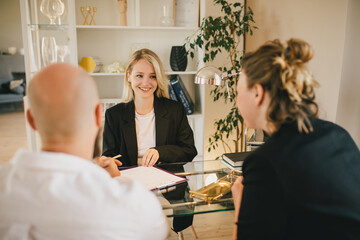 Happy couple having conversation with real estate agent in the office.