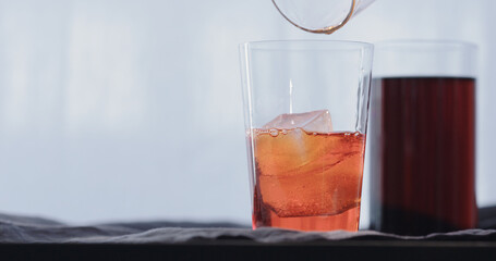 making cocktail aperetivo in tumbler glass with window on background