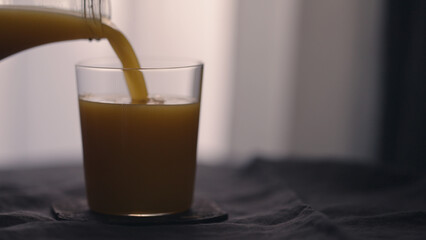 man pour orange mango juice in tumbler glass on linen cloth