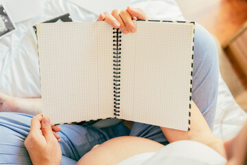 Baby list pregnant woman. Young pregnancy mother holding notepad. Pregnant lady writing check list...