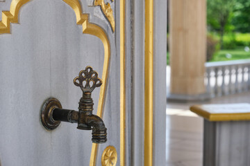 water metal faucet in the mosque decorated with beautiful patterns