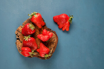 Ugly strawberries, top view, selective focus. Unusual organic strawberries. Deformed fruits strange...