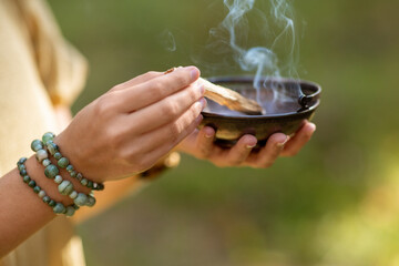 occult science and supernatural concept - close up of woman or witch with smoking palo santo stick...