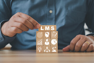 Hand arranging wood block stacking with icon LMS symbols on beautiful light background with copy space. Online business education. LMS Learning Management System concept.