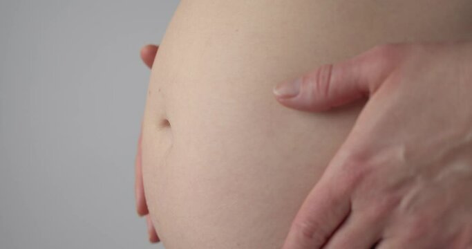 Belly of a Pregnant Woman, Isolated Closeup with Grey Background