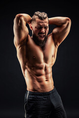 Naked strong man showing his abs on dark background. Strength and motivation